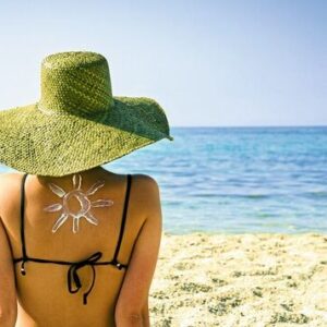 Woman on beach with sun symbol on her back - UV protection concept